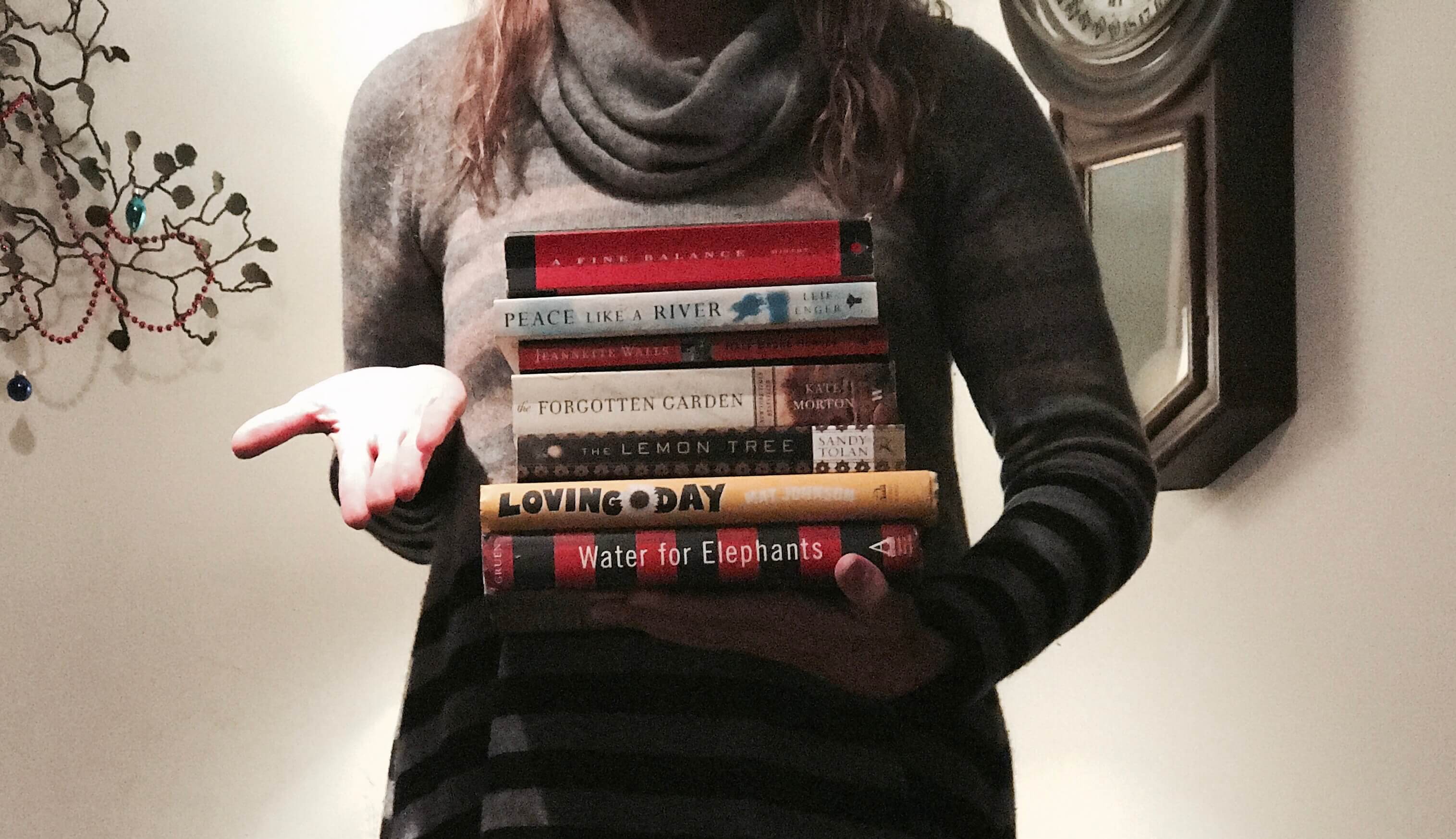 THe Novel Tourist holding a stack of book club book choices