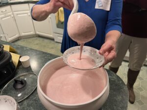 scooping up strawberry soup from a large bowl into a small bowl for the soup swap