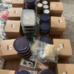 collection of soups in containers ready for the book club soup swap and beside each stack is a brown box for the raffle tickets 