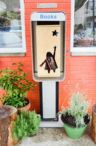 LIttle Free Library in Philadelphia Italian Market area. Brick building in the back with an old repuposed phone booth as the little library