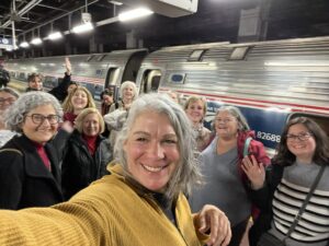 Book Club members ready for an adventure on Amtrak with train in the background